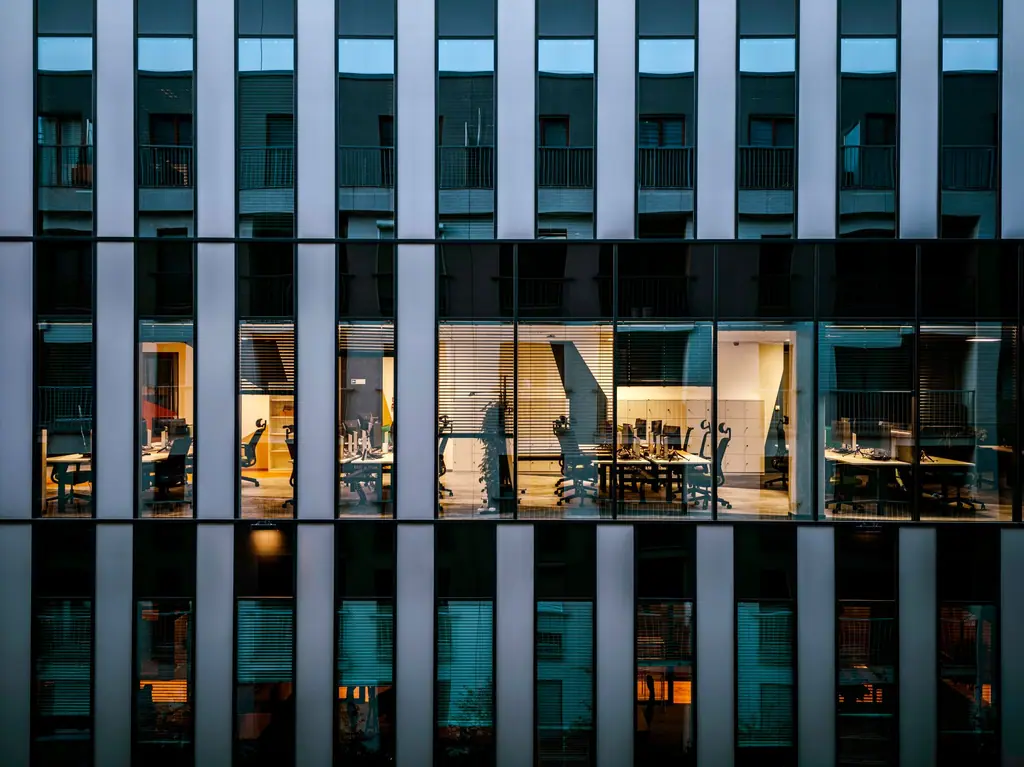 Glass office facade with lit workspaces behind it